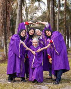 a group of women in purple dresses standing next to each other and making a heart with their hands