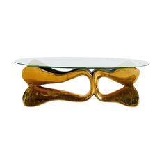 a glass and gold coffee table with two wavy legs