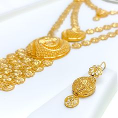 The Layered Dangling Flower 5-Piece Necklace Set, crafted from 21k yellow gold and weighing 83.5 grams, is a masterpiece of jewelry design. This luxurious ensemble features a 26-inch necklace with a dramatic 4.5-inch drop and 4-inch adjustable links, secured by a hook lock. Complemented by matching 1.6-inch earrings with hook backs, a 7.5-inch bracelet with 1-inch adjustable links, and a size 9 ring, all with the same captivating flower motif. This comprehensive set is perfect for those who desi Gold Hand Set Long Bridal Necklace, Opulent Gold Necklace For Festive Season, Ceremonial Yellow Gold Jewelry Sets, Opulent Gold Jewelry For Ceremonial Occasions, Opulent Gold Ceremonial Jewelry, Opulent Gold Necklace With Hand-set Details, Gold Bridal Necklace Hand Set, Gold Long Bridal Necklace Hand Set, Opulent Gold-plated Gold Jewelry