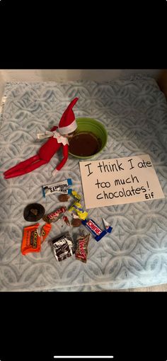 an elf is sitting on top of a bed with candy and candies in front of him