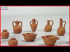 nine clay vases sitting on top of a white table next to eachother