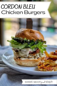 a chicken burger with lettuce and cheese on a plate next to some fries