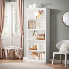 a white bookcase in a living room next to a window