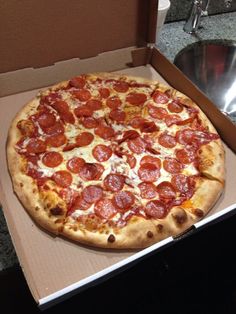 a pepperoni pizza sitting in a box on the counter