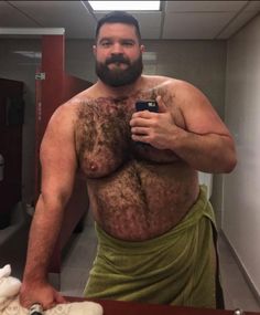 a man with no shirt is taking a selfie in the mirror while wearing a towel