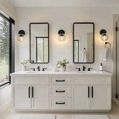 a white bathroom with double sinks and mirrors