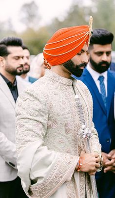 a man wearing an orange turban standing next to other men