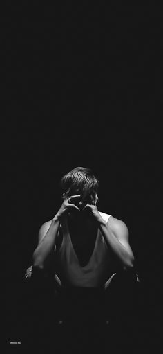 a black and white photo of a woman covering her face with her hands in the dark