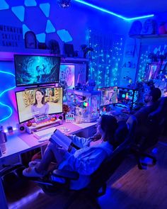 two people sitting in chairs watching tv at night with blue lights on the walls and floor