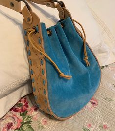 a blue handbag sitting on top of a bed next to a white comforter