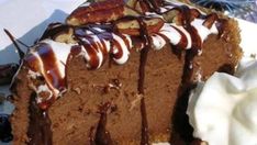 a piece of chocolate cake on a plate with whipped cream and pecans in the background