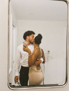 a man and woman standing in front of a mirror