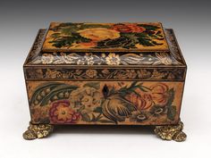 an ornately decorated box with flowers and leaves on the lid is sitting on a white surface