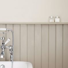 a white bath tub sitting next to a wall with two candles on top of it