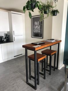 a kitchen table with two stools and a potted plant on the wall above it