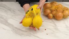 a person holding two small yellow stuffed animals on top of a counter next to onions