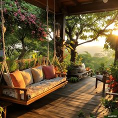 a porch swing with pillows on it in the sun setting over some trees and flowers