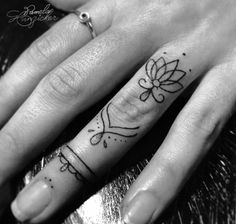 two fingers with tattoos on them, one has a flower and the other has a bow