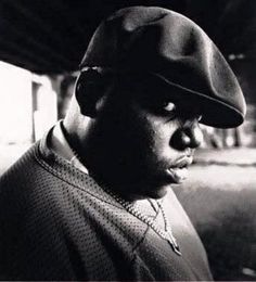 a black and white photo of a man in a hat looking off into the distance