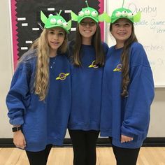 three girls wearing blue sweatshirts with green hats on their heads and one girl in black leggings