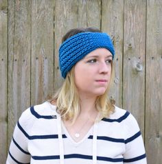 a woman wearing a blue headband in front of a wooden fence