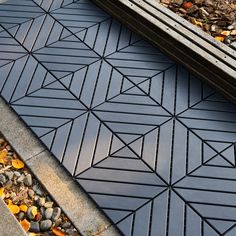 a close up of a black tile floor with leaves on the ground next to it