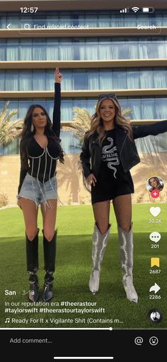 two women standing in front of a tall building with their arms up and legs crossed