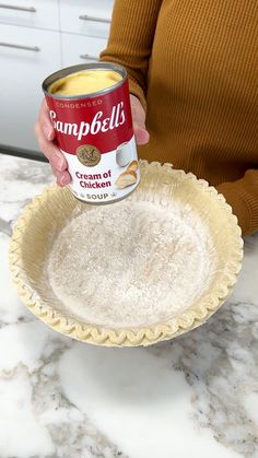 a woman holding a can of soup in her hand on top of a marble counter