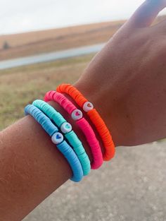 a person's arm with three bracelets on it and two eyeballs in the middle