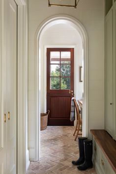 an arched hallway leading to a door with a bench in the middle and a window on the far side