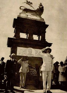 two men standing in front of a tall tower with a lion on it's top