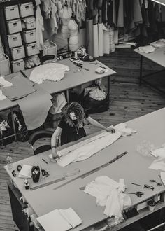 a woman is working in an art studio with lots of crafting supplies on the table