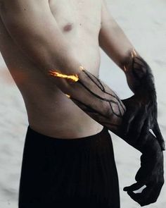 a man wearing black gloves with flames on his arm and hands, holding something in the other hand