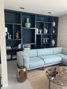 a living room filled with lots of furniture next to a wall mounted bookshelf