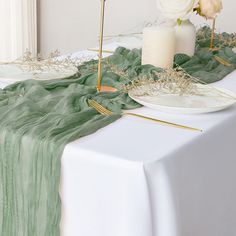 the table is set with white flowers and greenery