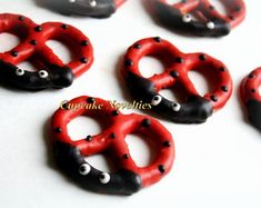 six red and black heart shaped buttons with eyeballs on each one, sitting on a white surface