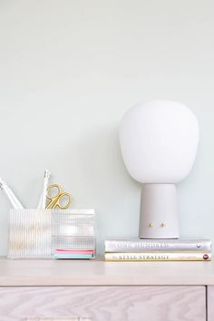 a white lamp sitting on top of a wooden desk next to a pile of books