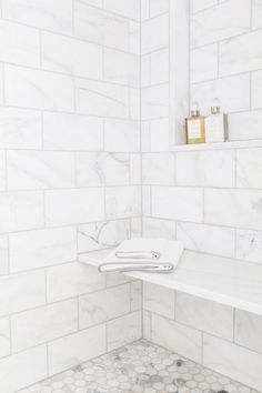 a bathroom with white marble walls and flooring that has hexagonal tiles on the wall