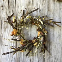 a wreath made out of dried flowers and leaves sitting on top of a wooden fence