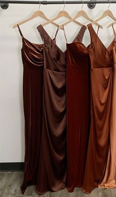 four dresses hanging on a rack in front of a wall