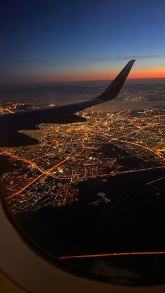 the view from an airplane window at night, looking down on a city and its lights