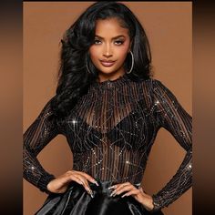 a woman wearing a black dress with sequins on the top and bottom, standing in front of a brown background