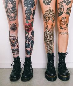 two women with tattoos on their legs standing next to each other, both wearing black combat boots