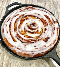 a cinnamon roll in a skillet with icing on the top is ready to be eaten