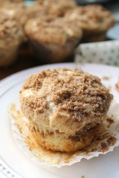 two muffins sitting on top of a white plate next to other muffins