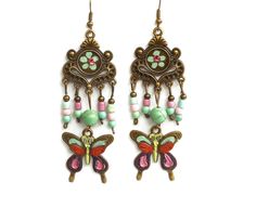 "A vibrant addition to any outfit, these earrings feature butterfly charms that are accented in eye-grabbing colors that dangle below turquoise magnesite beads! Above, pendants that are decorated with painted blue flowers and feature swinging beads add whimsical movement! Little pink Swarovski crystal rhinestones add a bit of sparkle from within the flowers for a touch of glam! Unique and comfy...they are super lightweight so no annoying pulling on your ears as they sway! The perfect pair of ear Butterfly Boho, Whimsical Earrings, Pink Swarovski, Colorful Butterfly, Art Nouveau Jewelry, Saint James, Hippie Jewelry, Butterfly Charm, Chic Jewelry