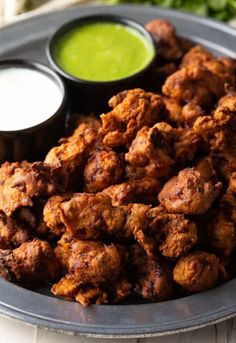 a plate filled with fried food next to dipping sauces