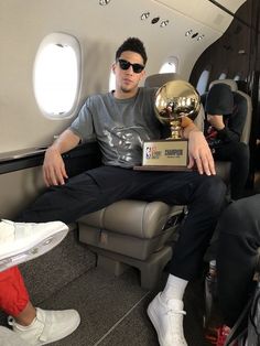 a man sitting on an airplane holding a trophy