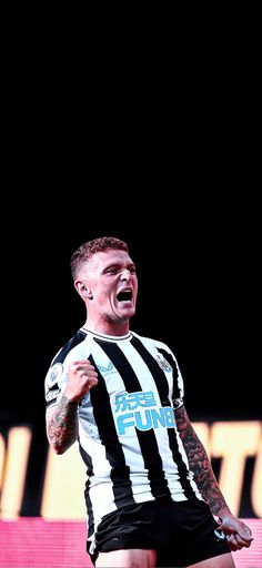 a man in black and white striped shirt holding a soccer ball with his mouth open