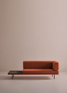 an orange couch sitting on top of a white floor next to a wooden coffee table